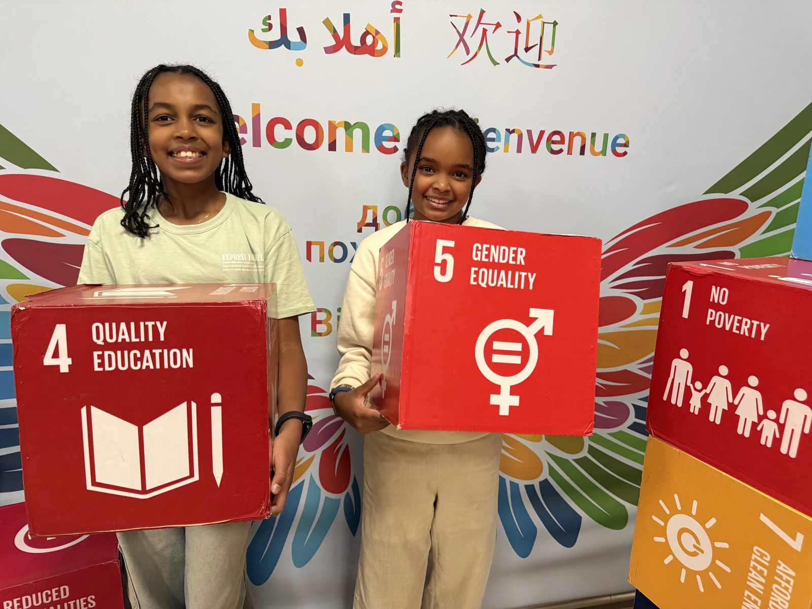 Surina and Keisha holding UN Sustainable Development Goal boxes for Quality Education and Gender Equality